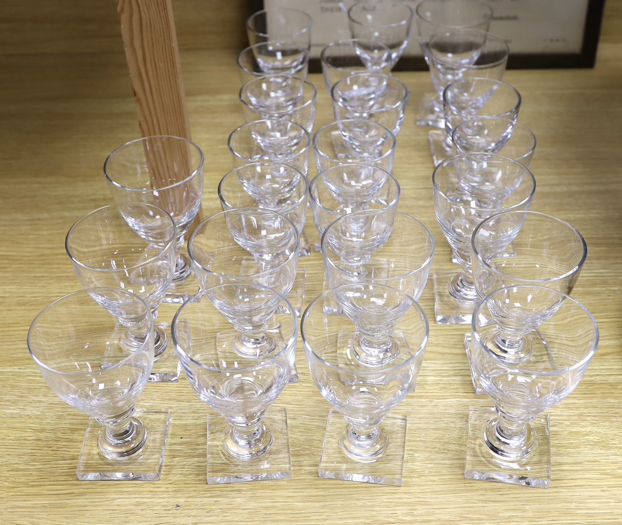 A set of twelve large square based glass rummers and a set of twelve similar smaller examples